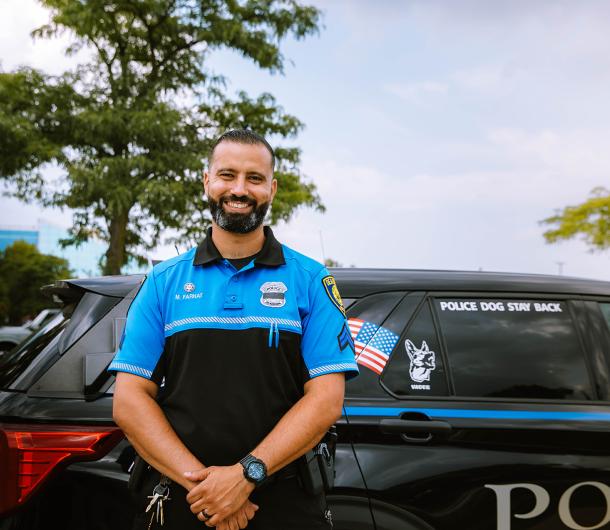 Neighborhood police officer Farhat poses in front of a Dearborn Police vehicle. 