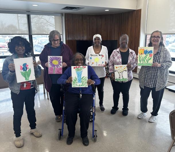 Residents of a senior housing building pose with their artwork after a group activity. 