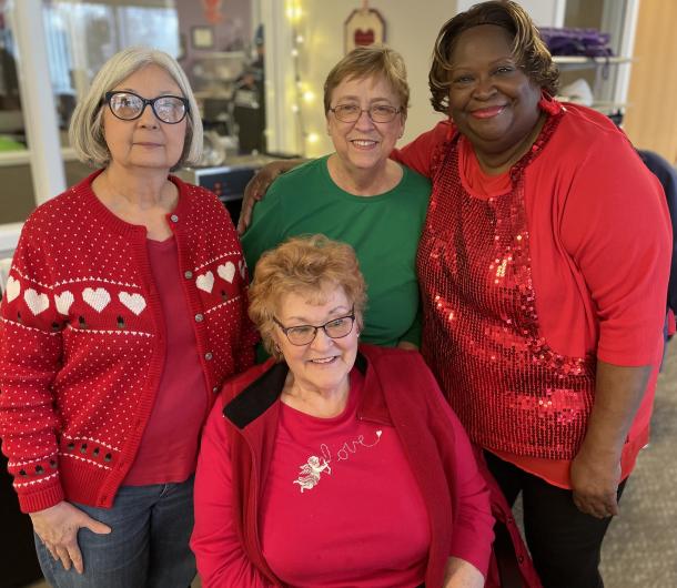 Four Senior Housing building residents pose together at a holiday luncheon. 